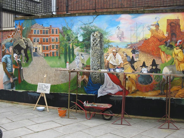 Colorful historical mural on an urban street with painting tools.Colorful street mural with artist's supplies in the foreground.