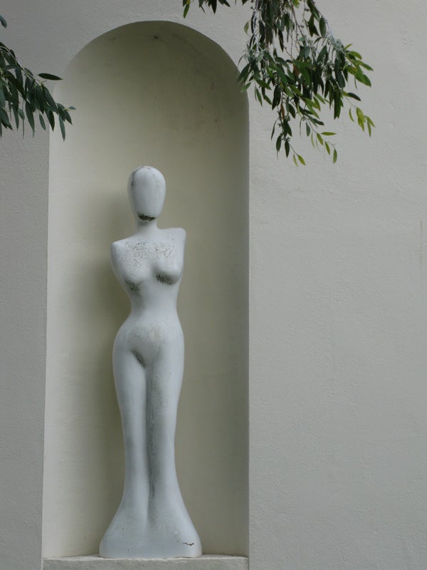 Abstract mannequin statue in a niche with foliage.Abstract mannequin statue in a wall niche.