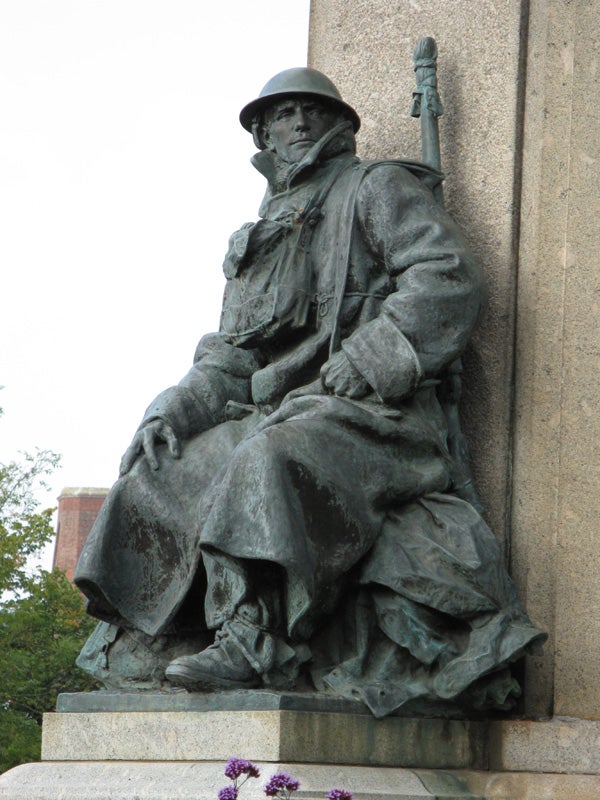 Statue of a seated soldier with a rifle.Bronze statue of a soldier with a rifle sitting on a base.