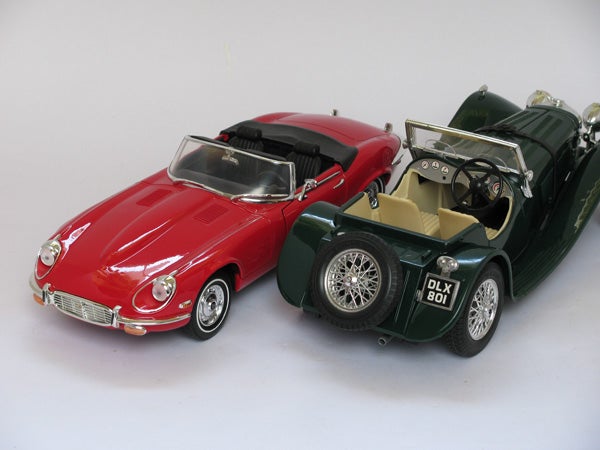 Two model cars, a red Jaguar E-Type and a green classic sports car.