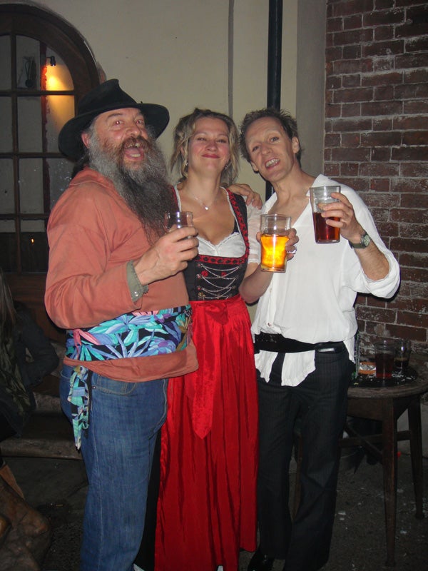 Three people toasting with drinks at a party.