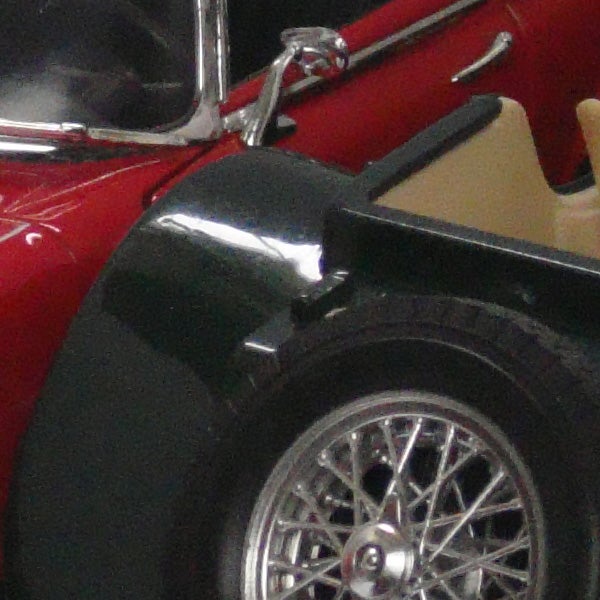 Close-up of a red vintage car model wheel and headlight.