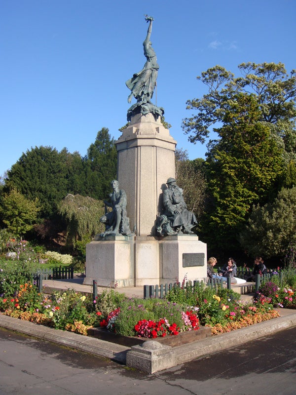 Monument surrounded by colorful flowers and sitting people