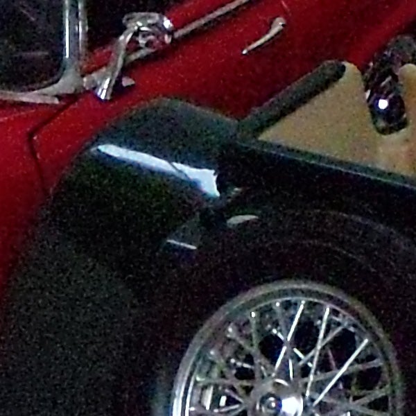 Close-up photo of a vintage car's shiny black fender and chrome wheel.