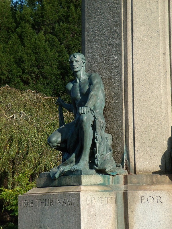 Bronze statue of a seated figure next to an inscription.