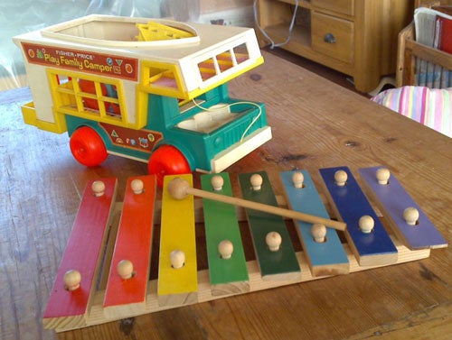 Colorful wooden toy xylophone and camper van on a table.