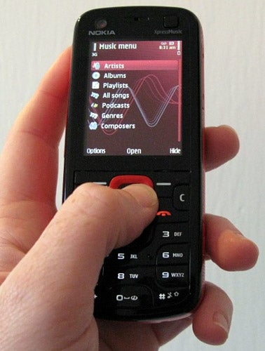 Hand holding a Nokia 5320 XpressMusic showing music menu.
