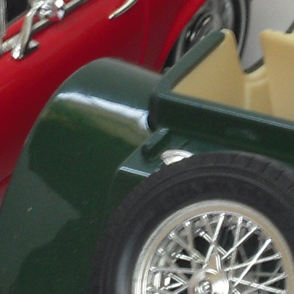Close-up of a green toy car's wheel and fender.