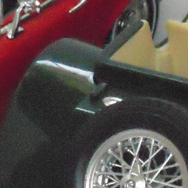Close-up of a classic car's chromed wheel and fender.