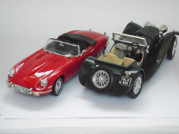 A red and a green vintage toy car models on white background.