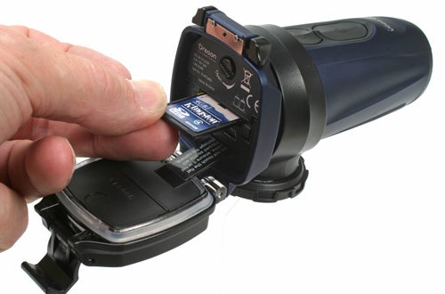 Hand inserting memory card into Oregon Scientific ATC5K Action Camera.