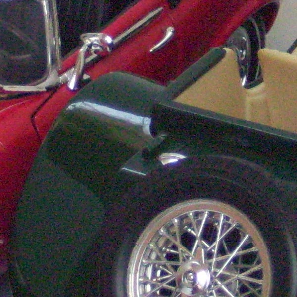 Close-up of a black vintage car's side with chrome details.