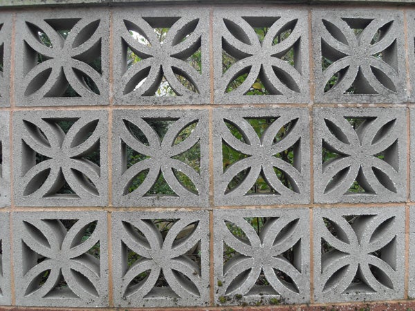 Decorative concrete block wall with floral pattern.
