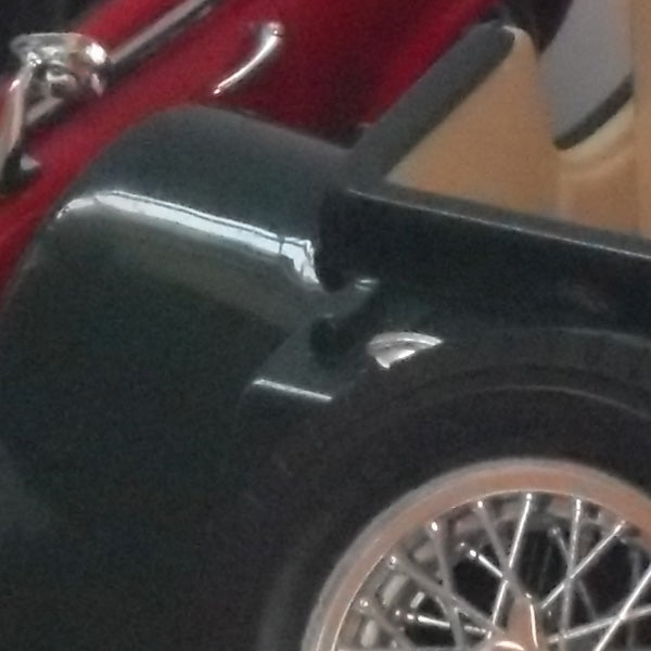 Close-up of a red car's side and wheel.