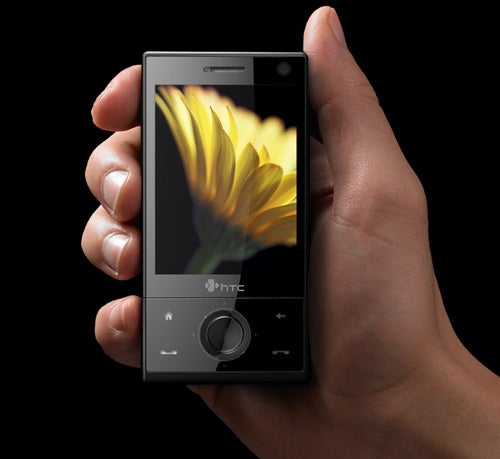 Hand holding HTC Touch Diamond smartphone with flower wallpaper.