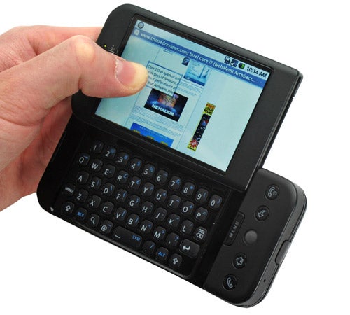 Hand holding T-Mobile G1 Android Smartphone with keyboard open.