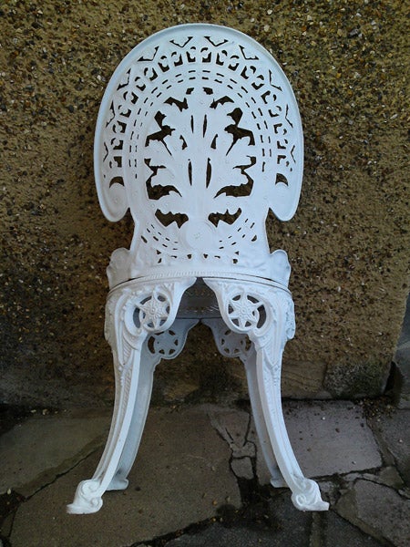 White ornate garden chair on a brick surface.