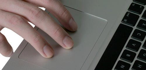Close-up of fingers on Apple MacBook's trackpad and keyboard.