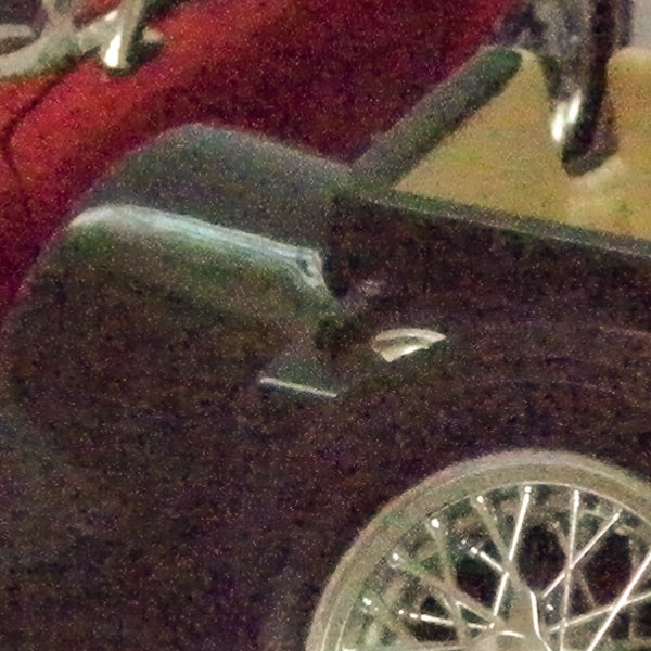 Photo of a red vintage car reflected on a surface.