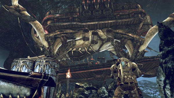 Scene from Gears of War 2 with soldier and monstrous structure.