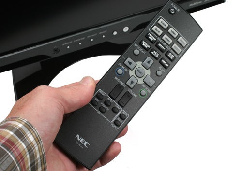 Hand holding NEC MultiSync monitor remote control.