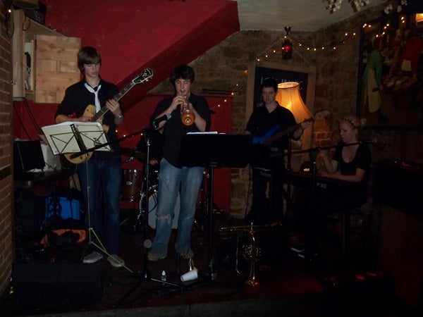 Band performing in a dimly lit venue with brick walls.