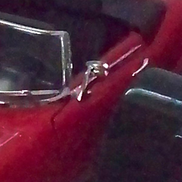 Close-up of a silver ring on a reflective red surface.