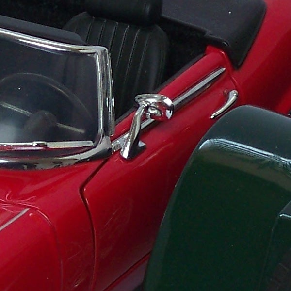 Close-up of a red toy car door and side mirror.