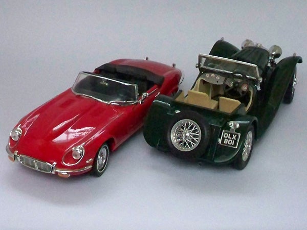 Toy models of a red car and a green car on gray background.