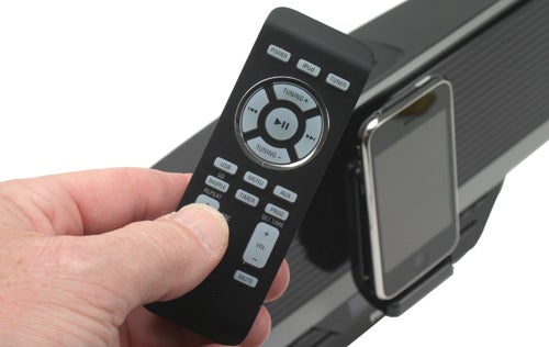 Hand holding remote in front of Philips DC910 docking station.
