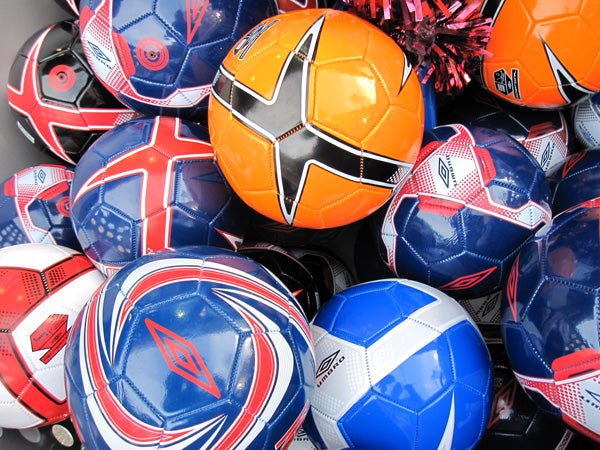 Assorted colorful soccer balls in a bin.