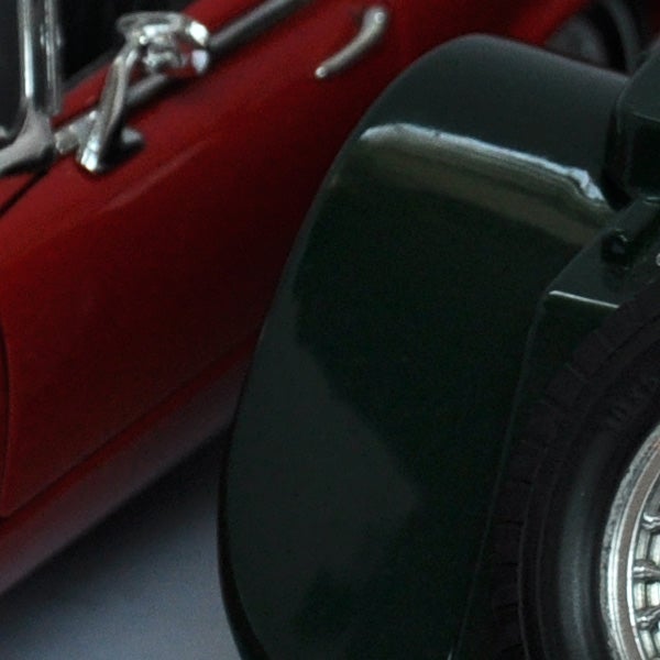 Close-up of a red toy car's side and wheel.