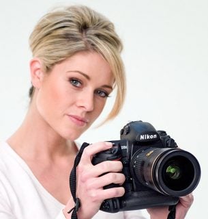 Woman holding a Nikon D3x DSLR camera.
