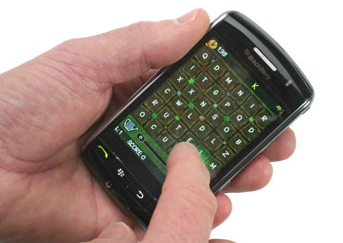 Hand typing on BlackBerry Storm smartphone's virtual keyboard.