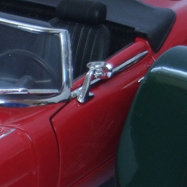 Close-up of red car's side mirror and door.