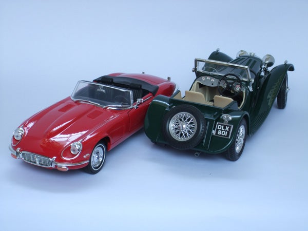 Red and green vintage model cars on light blue background.