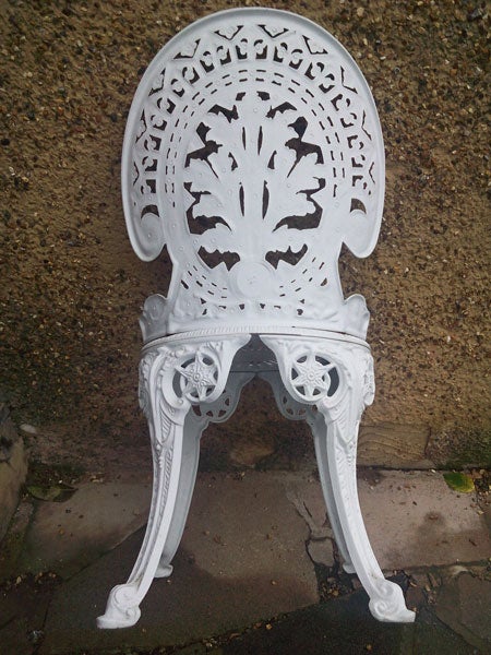 White ornate metal chair on a concrete surface
