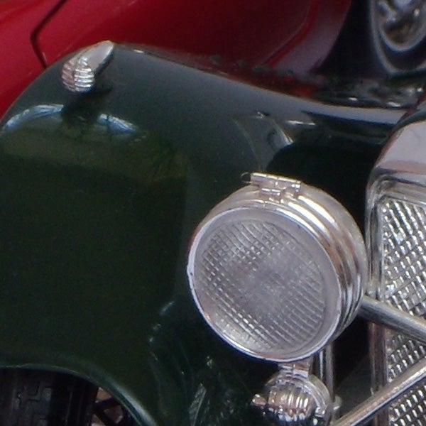 Close-up of a vintage car's headlight and grille.