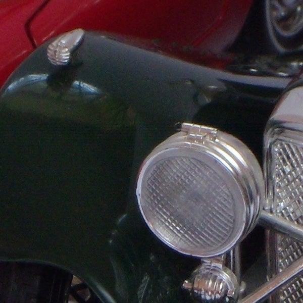 Close-up of vintage car's headlamp and grille.