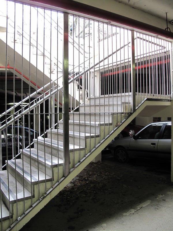 Concrete stairway in a parking garage with cars and railings