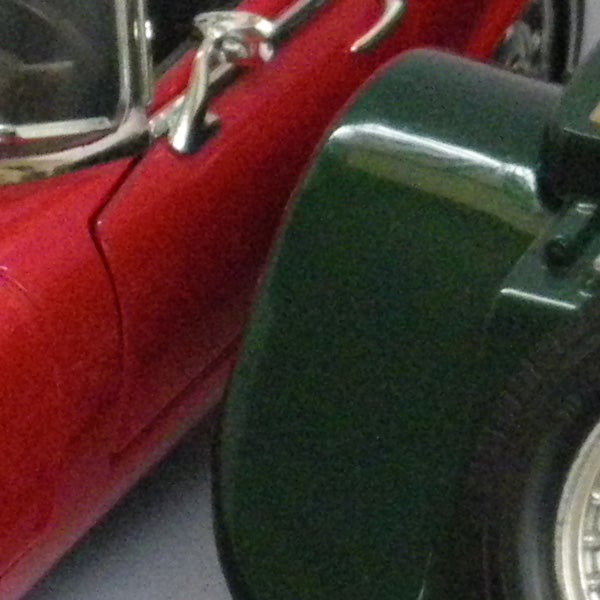 Close-up of a red and green vintage car wheels and doors.