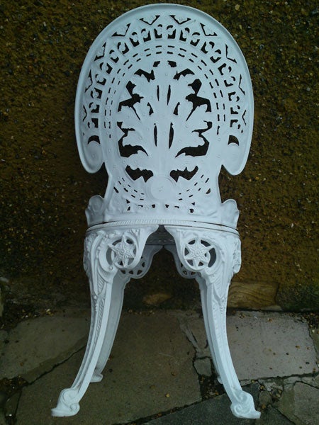 White ornate chair against a textured wall.