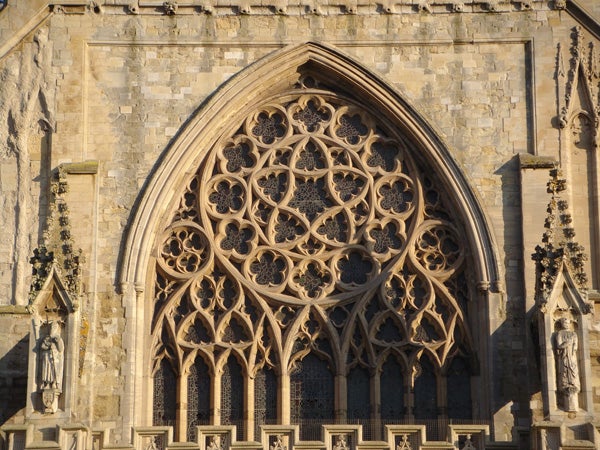 Intricate stone window tracery on Gothic cathedral facade.