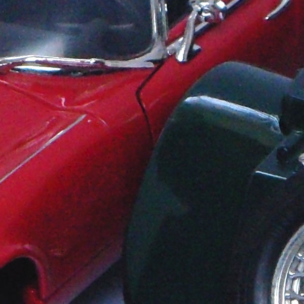 Close-up of red vintage car's side and rear wheel.