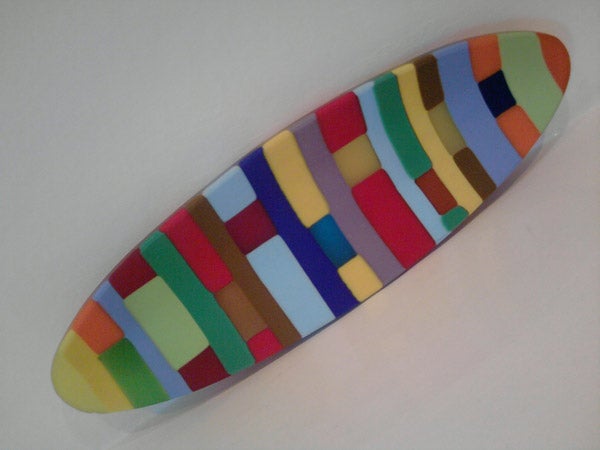 Multicolored patterned surfboard on a white background.