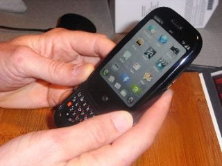 Person holding a Palm Pre smartphone with keyboard slid out.