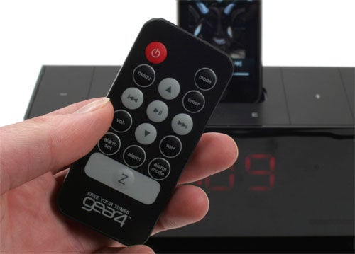 Hand holding Gear4 Blackbox 24/7 remote with device in background.