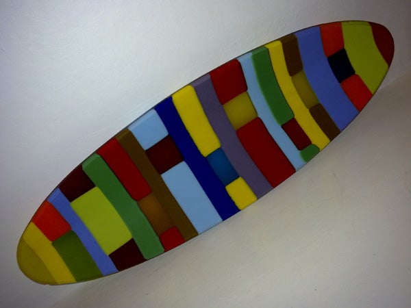 Colorful mosaic surfboard on white background.