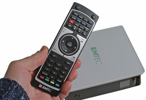 Hand holding Emtec Movie Cube S800 remote with device in background