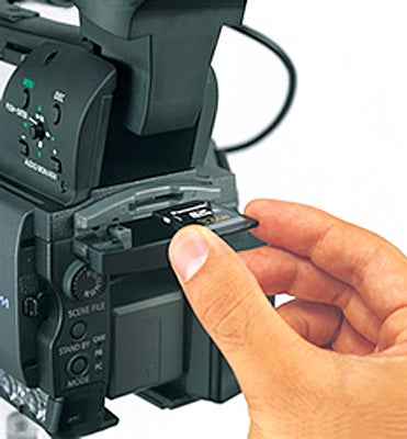 Hand inserting SD card into Panasonic AG-HMC151E camcorder.